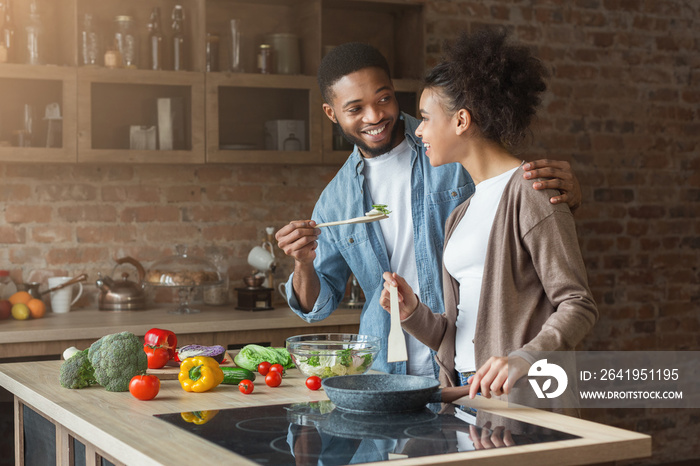 幸福的非裔美国人夫妇在厨房品尝晚餐