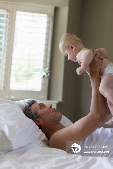 Father holding baby son in bed