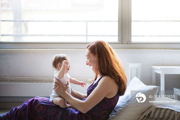 Side view of smiling mother sitting with her daughter at home