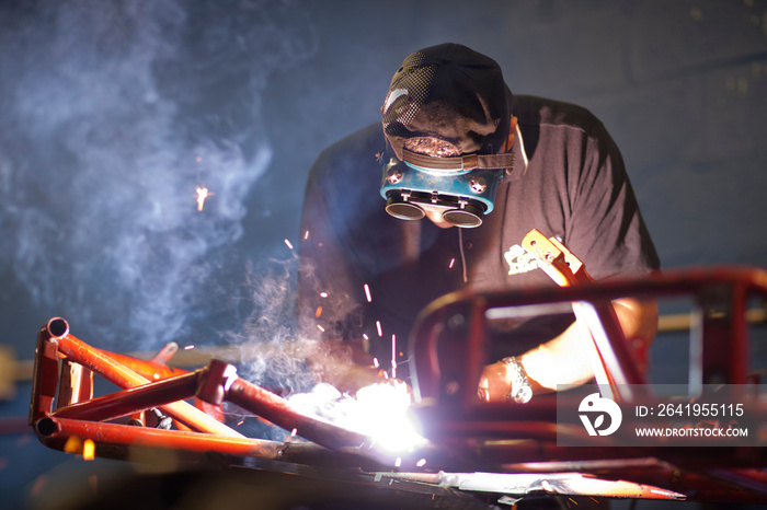 Mechanic welding go cart in workshop