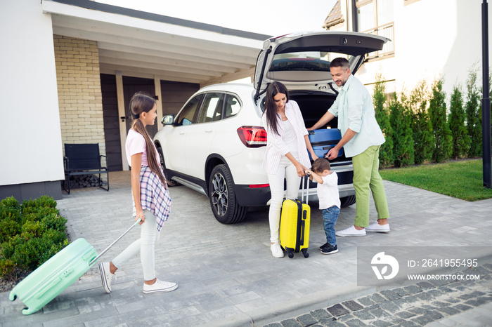 Full size photo of optimistic cute family pack baggage in car wear casual cloth near home outdoors