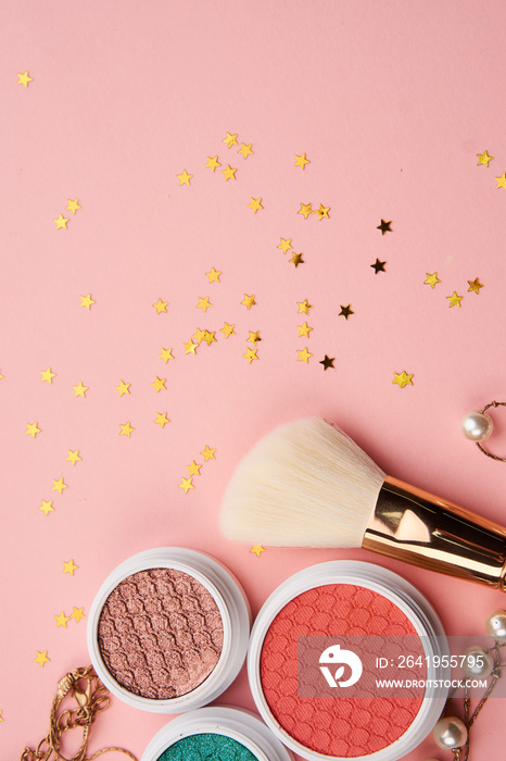 Eyeshadows and makeup brushes on a pink background Copy Space top view