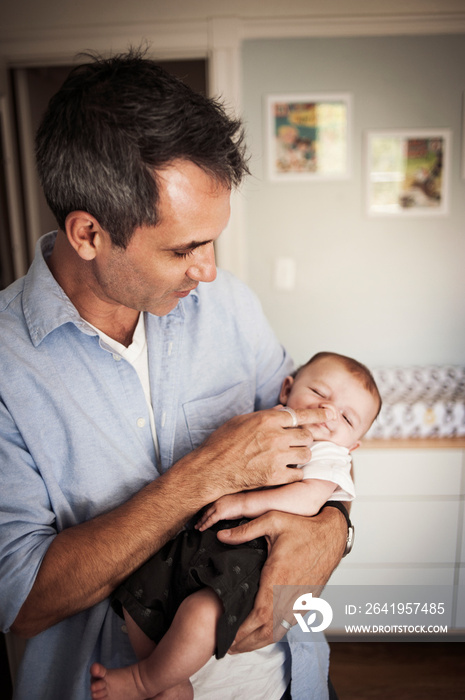 Father holding his baby son (2-5 months) in bedroom