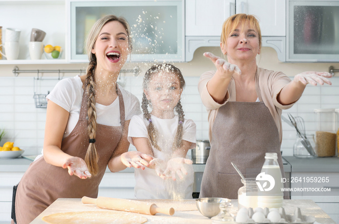 Young woman with mother and daughter cooking in kitchen