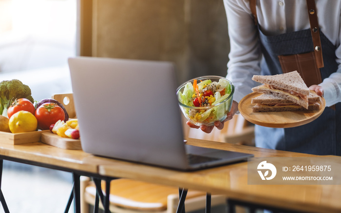 A woman videoblogger cooking and filming salad and sandwich in the kitchen, online learning cooking 