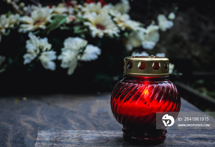 Single red candle on a grave on the cemetery in Warsaw, Poland