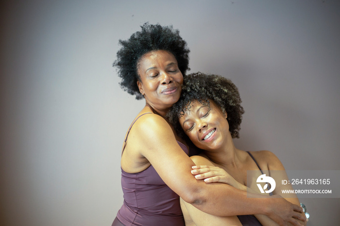 Studio shot of smiling mother and daughter wearing lingerie