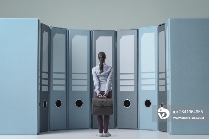 Businesswoman staring at the ring binders in the archive