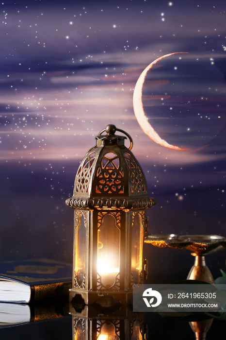 夜晚餐桌上闪烁的穆斯林灯和古兰经。斋月庆典