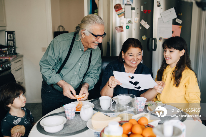 Grandparents admiring granddaughters greeting card at home