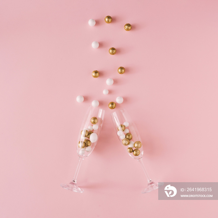 Champagne glasses filled with golden and white glitter decoration and pink background. Celebration m