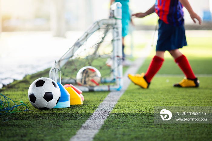 带模糊儿童足球运动员的足球和绿色人造草坪上的足球训练设备