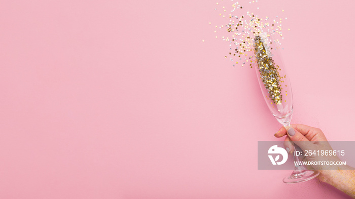 Woman holding champagne glass with gold confetti in hand