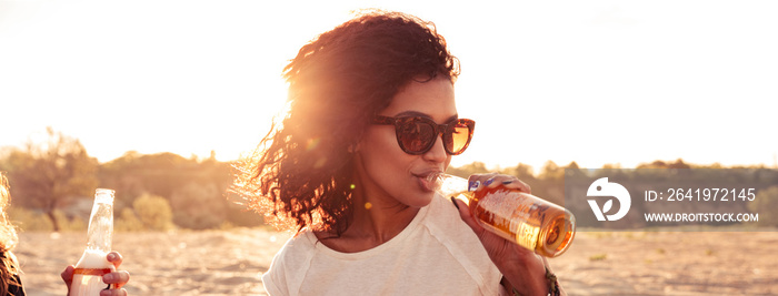 Young group of friends outdoors on the beach drinking beer.