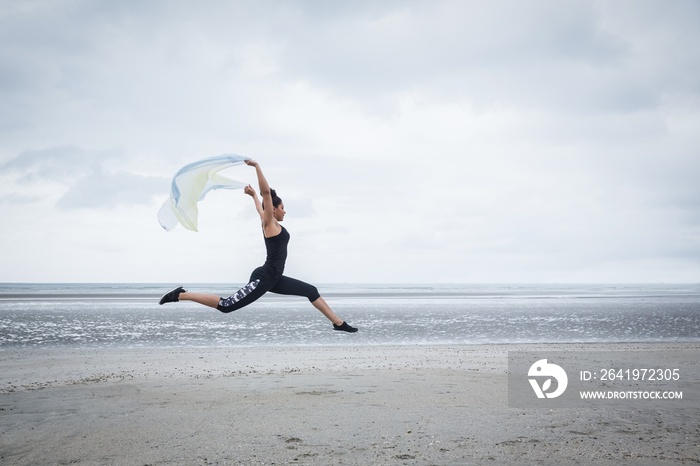 Fit girl leaping with scarf