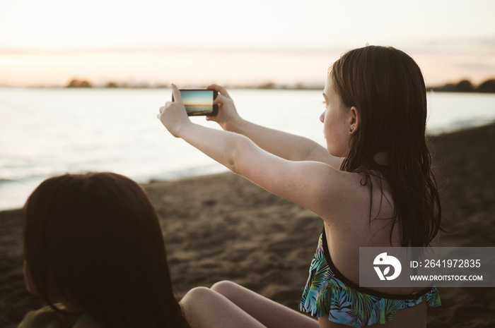 Girls (8-9,  12-13) taking photo on beach