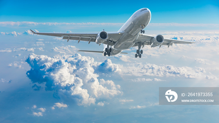 Commercial airplane flying above blue sky and white clouds.