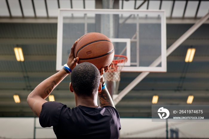 Rear view of young man throwing ball in hoop