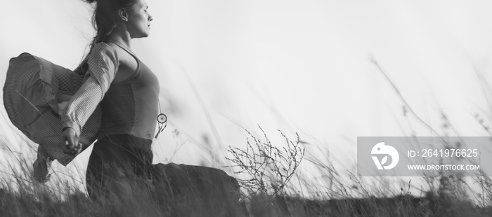 Monochrome portrait of a young woman sitting in a field enjoying the breeze and freedom from all thi