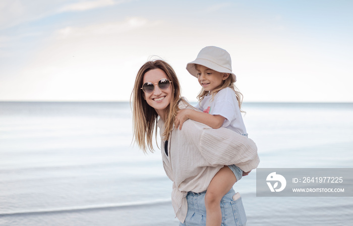 beautiful mom and her daughter at seaside smiling and have fun at the beach.