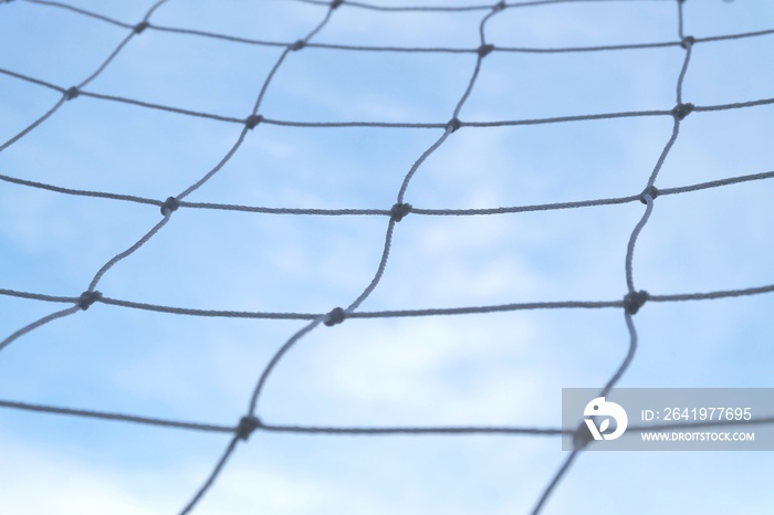 背景纹理为蓝天白云的足球球门的模糊白色网格尼龙网
