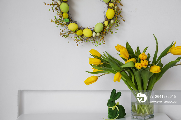 桌上放着郁金香和复活节兔子的花瓶，墙上有漂亮的花环