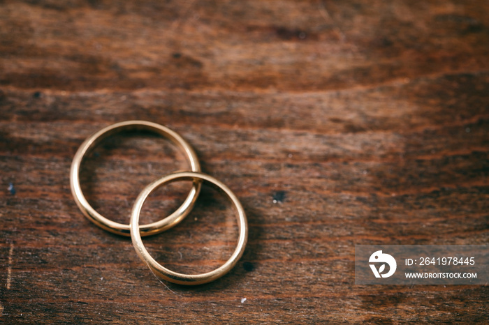 Two golden wedding rings on wooden background, copy space