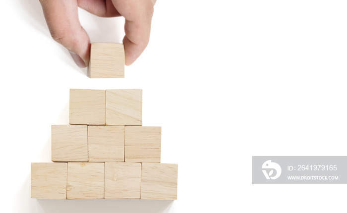 Hand arranging wood block stacking on top pyramid with white background. Business concept for growth