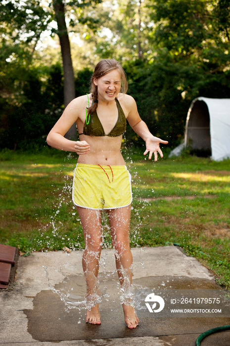 Water splashing on teenage girl at garden