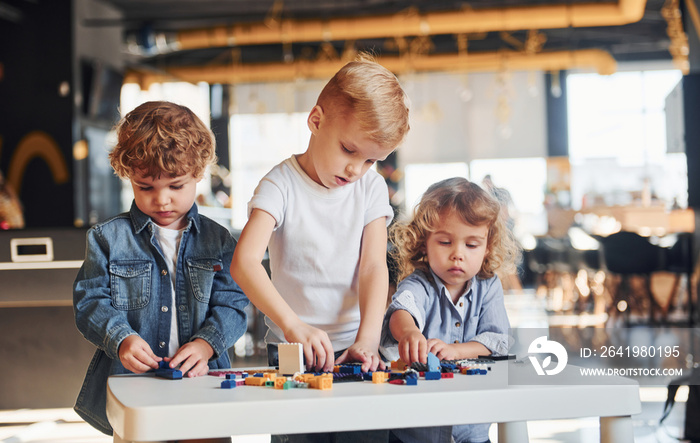 Little friends have fun with construction toys in playroom. Kindergarten educational games