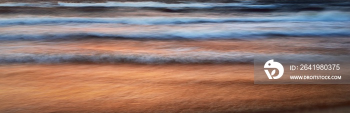 Colorful glowing sunset clouds above the sea after a thunderstorm. Dramatic sky. Waves and water spl