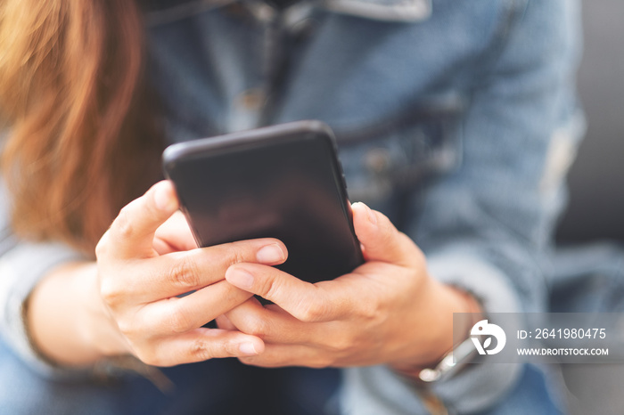 Closeup image of a woman holding , using and looking at smart phone