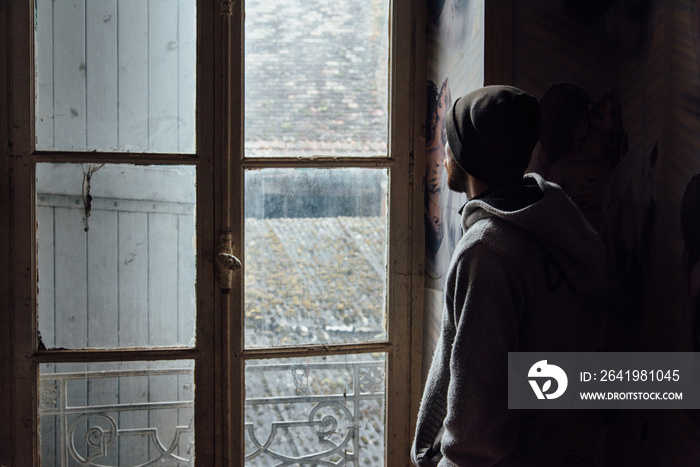 un vagabond sdf regarde par la fenêtre de son squat