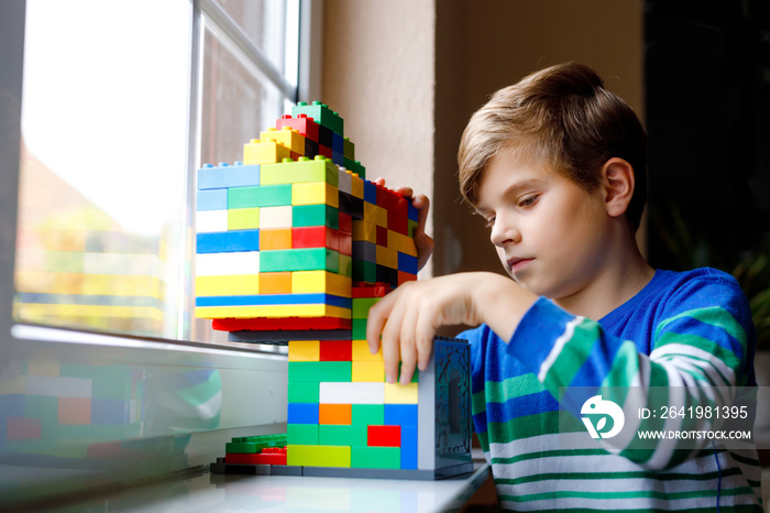 Little kid boy playing with lots of colorful plastic blocks. Adorable school child having fun with b