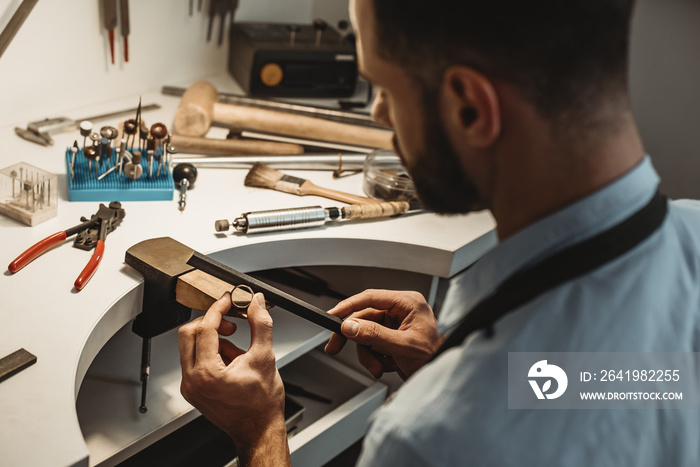 Delicate jewelry work. Close up of a male jeweler working and shaping an unfinished ring with a tool