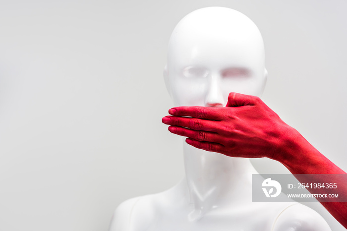 cropped image of girl in red paint covering mannequin mouth with hand isolated on white