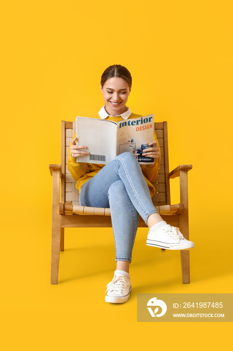 美女坐在黄色背景的木扶手椅上阅读杂志