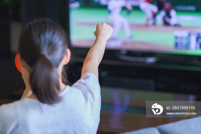 家でスポーツをテレビ観戦する若い女性のイメージ【プロ野球の動画配信サービス】