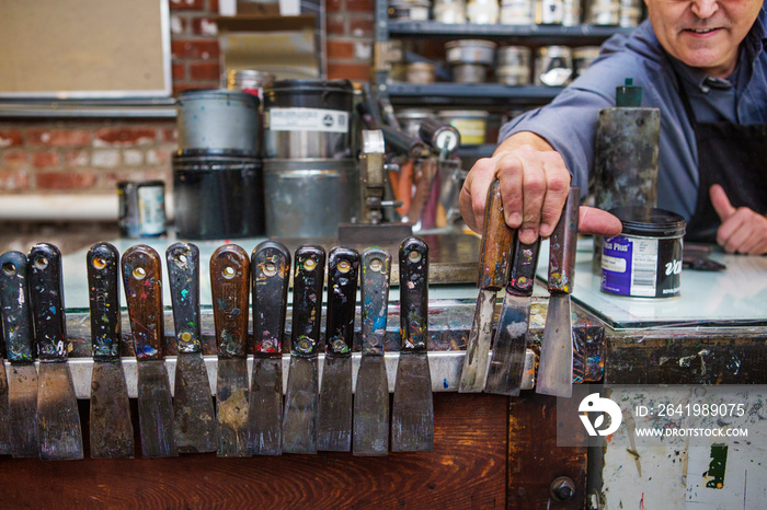 Printing house worker picking utility knife from row