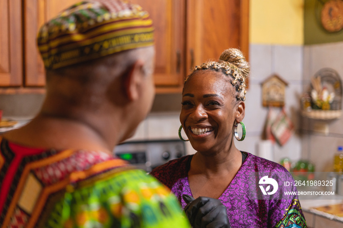 Imagen horizontal de una mujer afrocaribeña platicando muy sonriente  con su esposo en el interior d