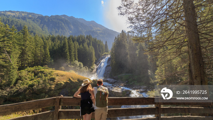 Junges Paar betrachtet die Krimmler Wasserfälle, die höchsten Wasserfälle Europas