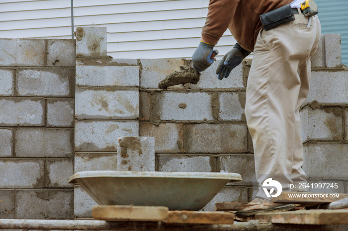 Construction worker laying of concrete blocks bricklaying new house wall