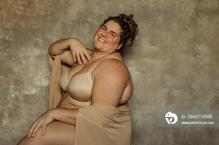 portrait of a plus size woman sitting sideways looking forward smiling