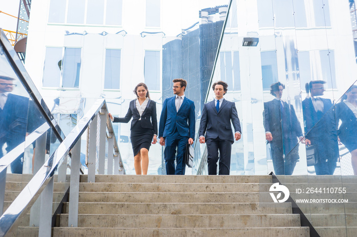 Confident businesspersons talking in front of modern office building. Businessmen and businesswoman 