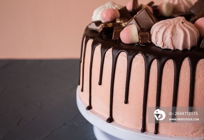 Biscuit cake with chocolate drips, marshmallows and marmalade, slice of chocolate. Sweets and food