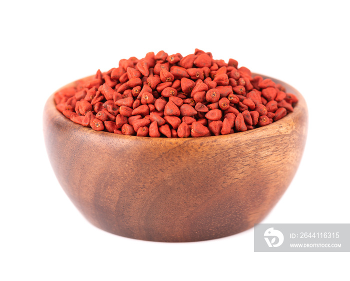 Annatto seeds in wooden bowl, isolated on white background. Achiote seeds, bixa orellana. Natural dy