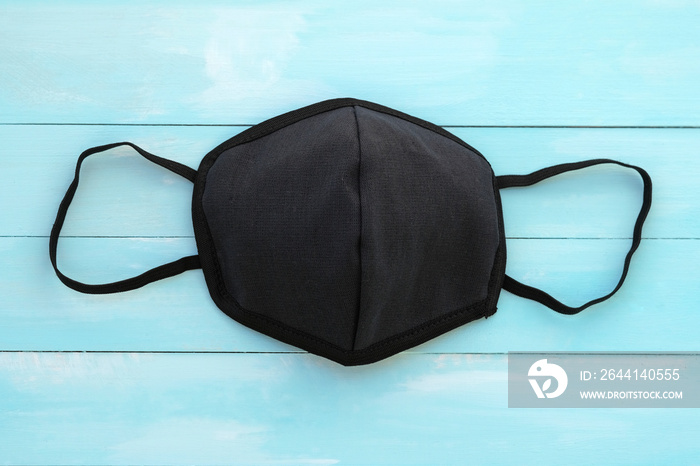 Black face mask on a blue wooden background top view. Mockup. Hand-sewn cotton face mask.