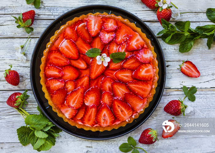 Delicious sponge cake with jelly and fresh strawberries on a wooden background.