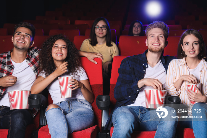 Friends with popcorn watching movie in cinema