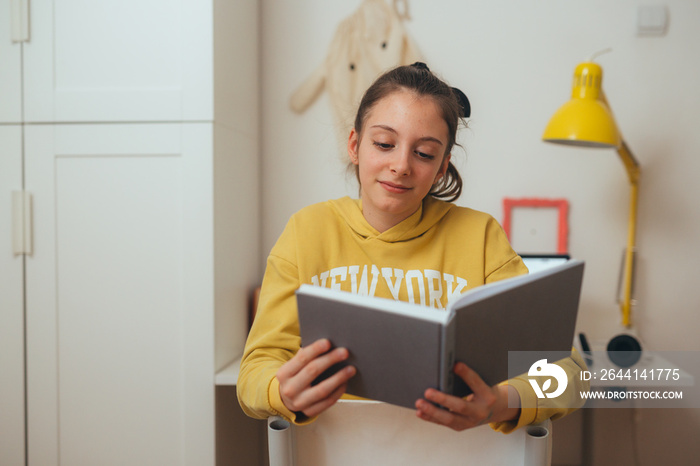 teenager girl sitting in her room, reading book